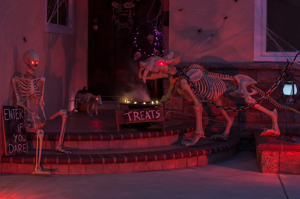 A small porch decorated for Halloween is lit by orange lights.