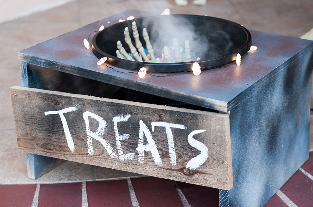 A DIY treat holder with LED skull lights and a skeleton hand sticking out of a foggy bowl.