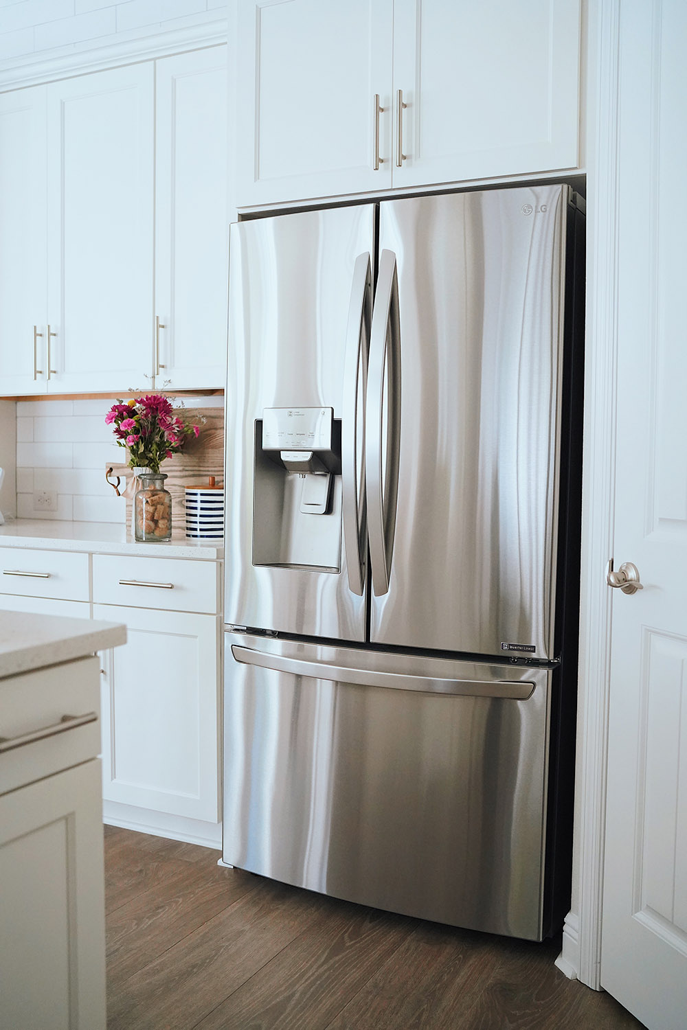A stainless steel LG refrigerator sits flush against white kitchen cabinets.