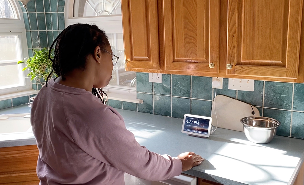 Woman looking at smart home device in kitchen.