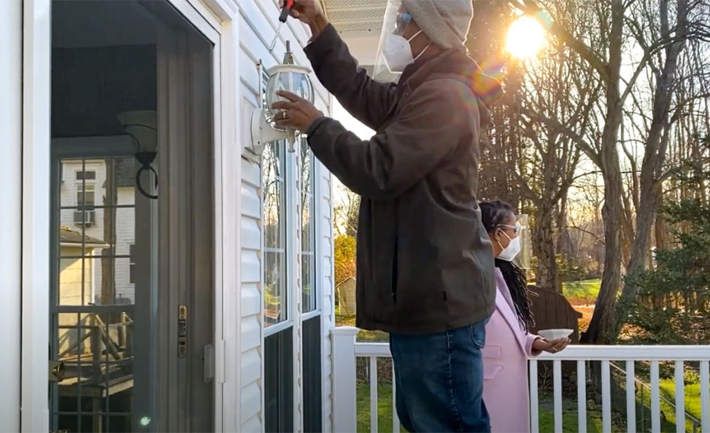 Man installing a smart home outdoor light fixture.