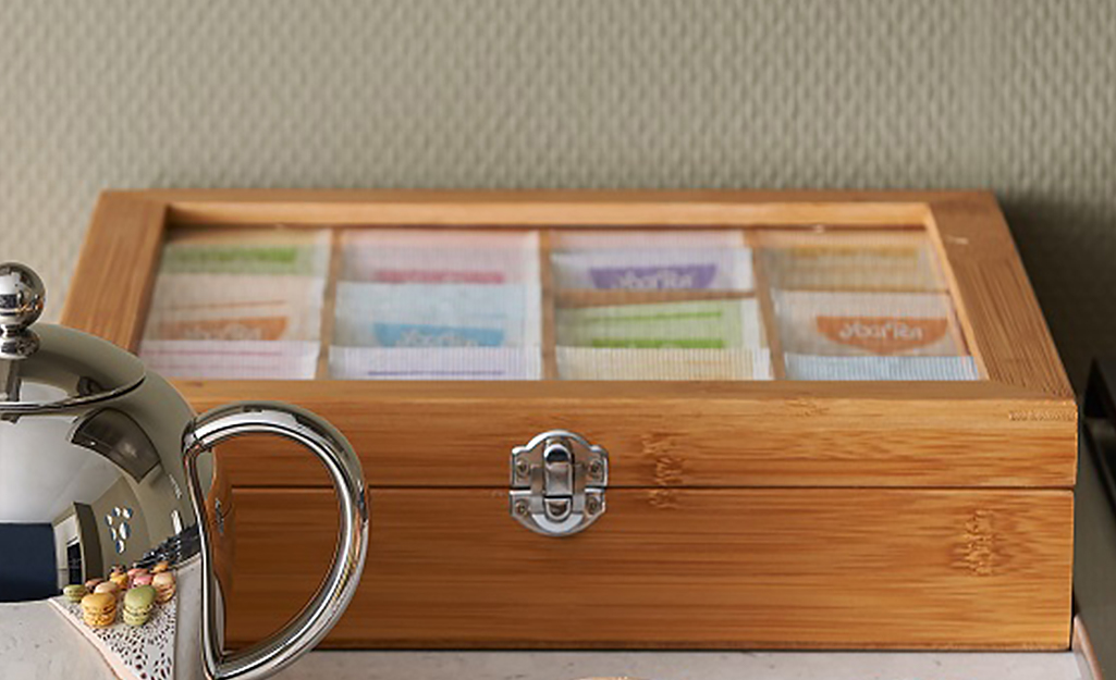 A tea box with a see-through lid containing spices and sitting on a countertop. A tea box with a see-through lid containing spices and sitting on a countertop.
