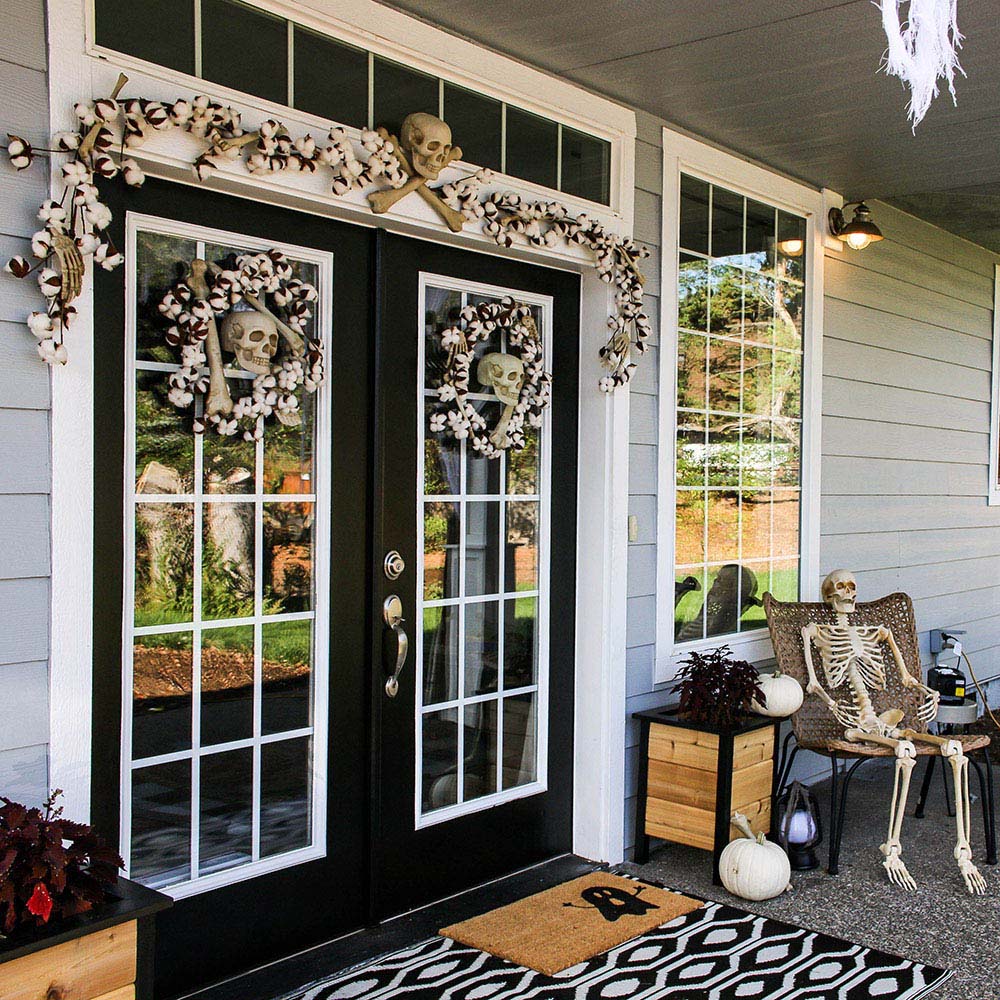 The front entrance of a home decorated for Halloween with a skeleton and skulls.