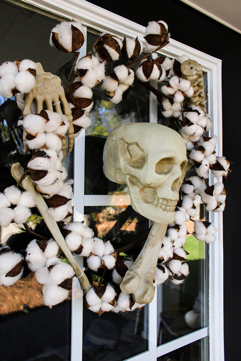 A door decorated with a skull and bones cotton wreath.
