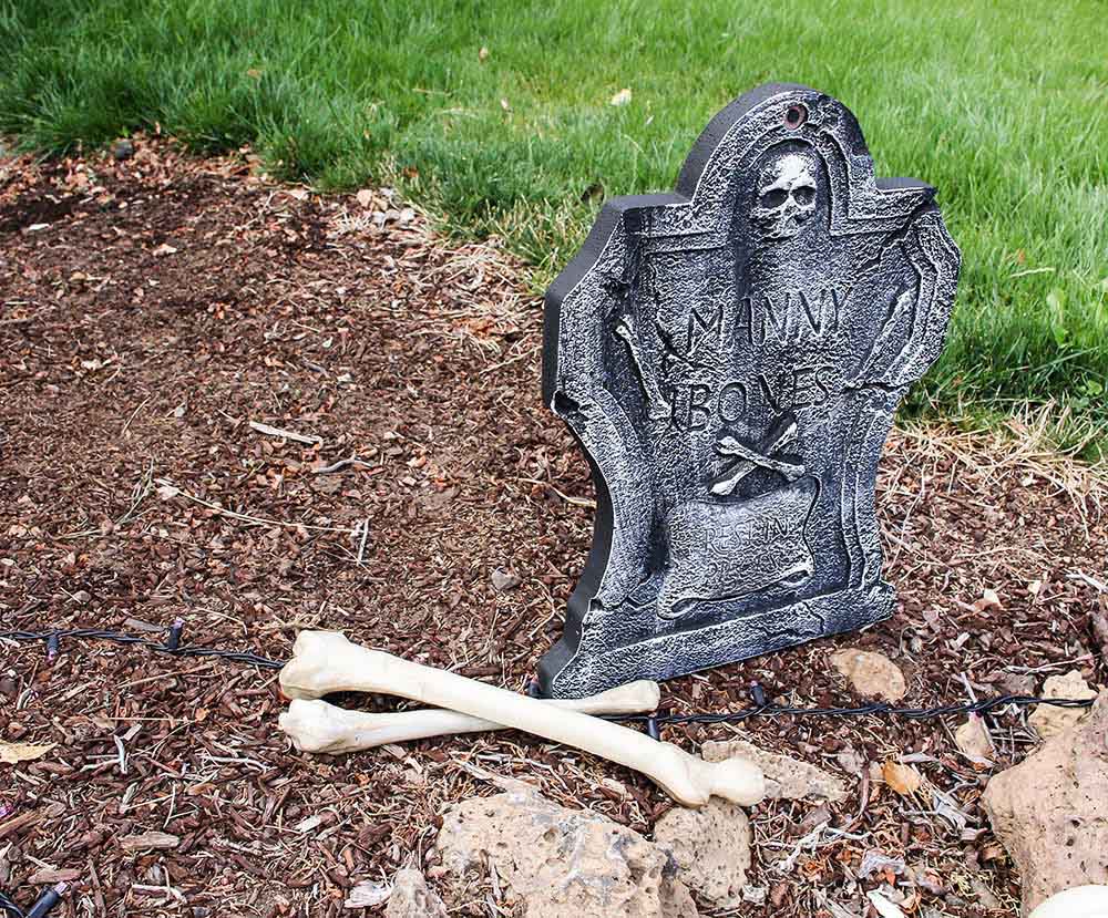 A flower bed turned into a cemetery with a tombstone and bones.