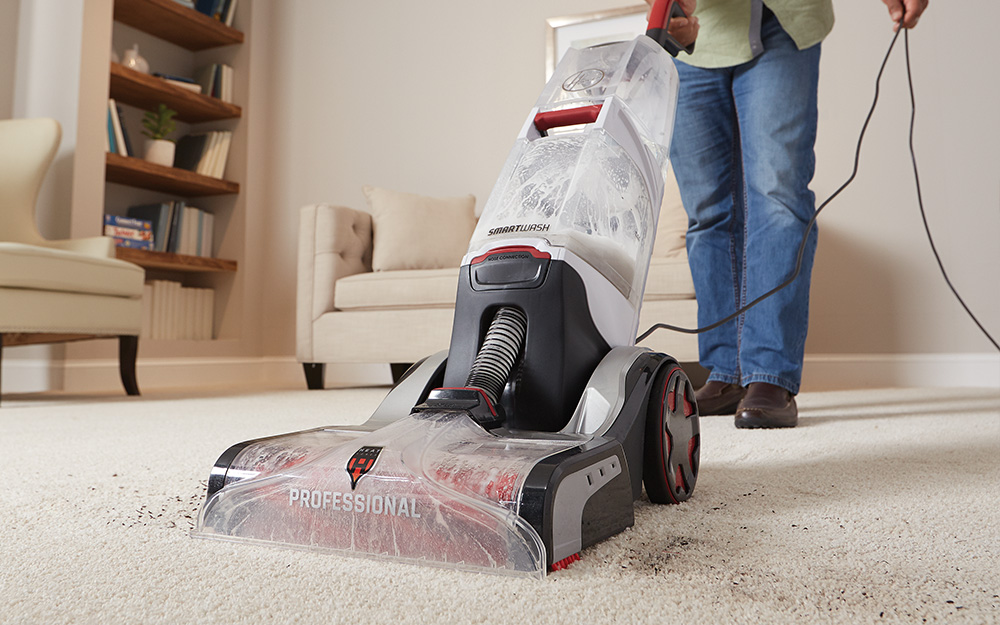 A person using a carpet cleaner to clean a carpet