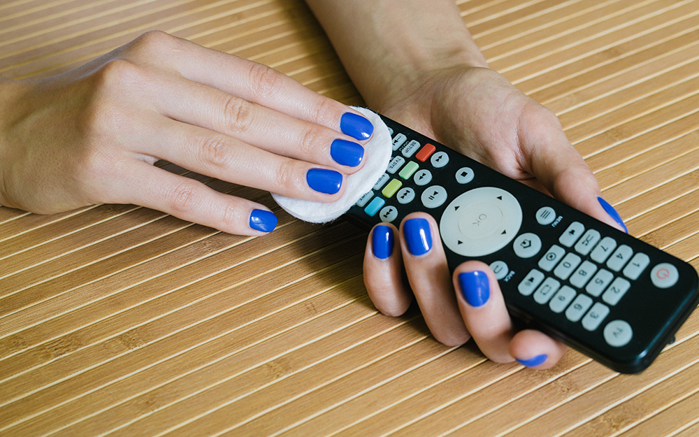 A person wiping and cleaning a remote control with a pad