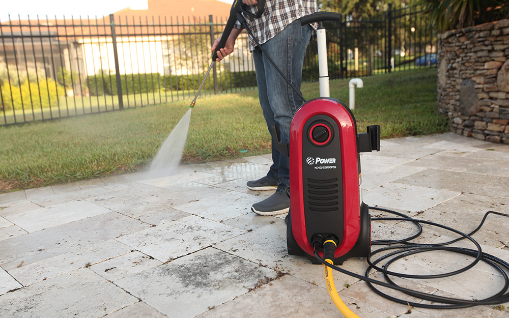 Someone using a pressure cleaner to clean a patio.