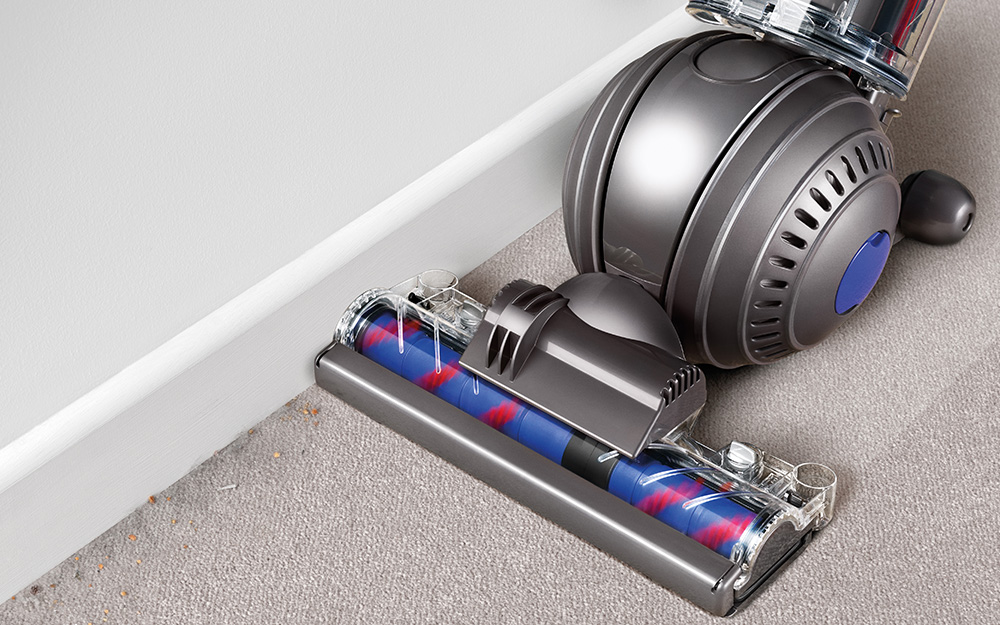Vacuum cleaner being used along baseboard.