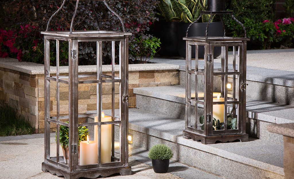A pair of metal outdoor lanterns with candles inside. A pair of metal outdoor lanterns with candles inside.