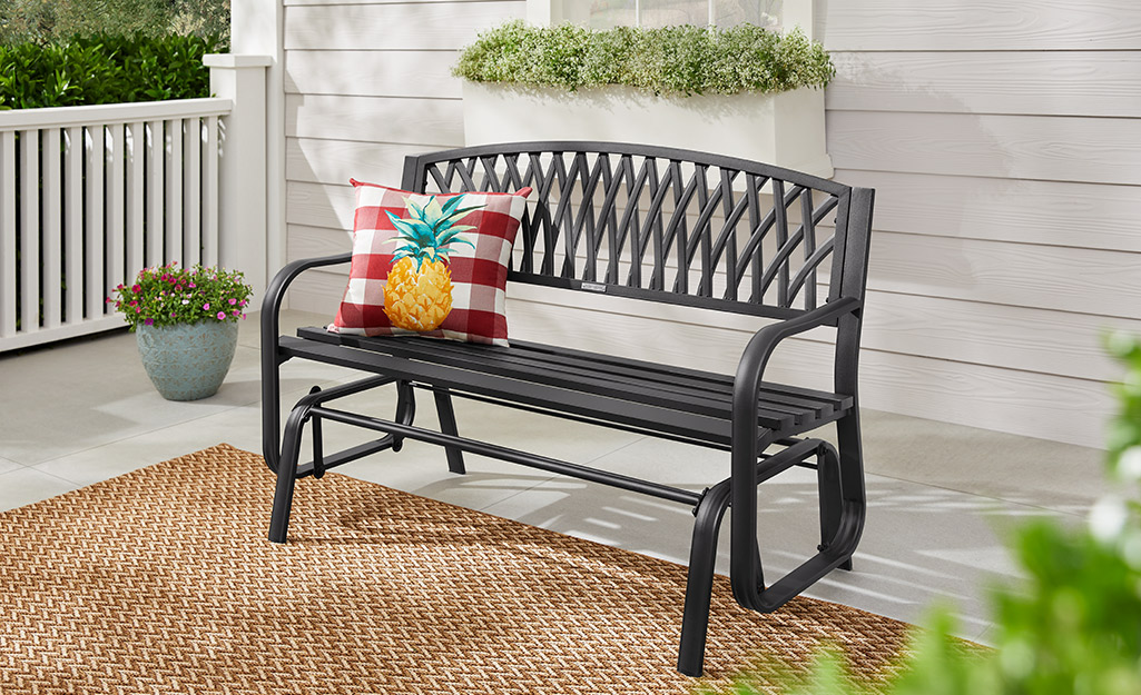 A black outdoor bench with an accent pillow. A black outdoor bench with an accent pillow.