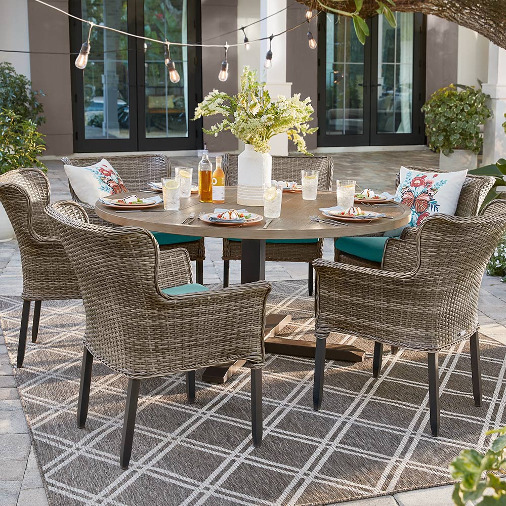 A patio table with plates and a floral arrangement and four chairs.