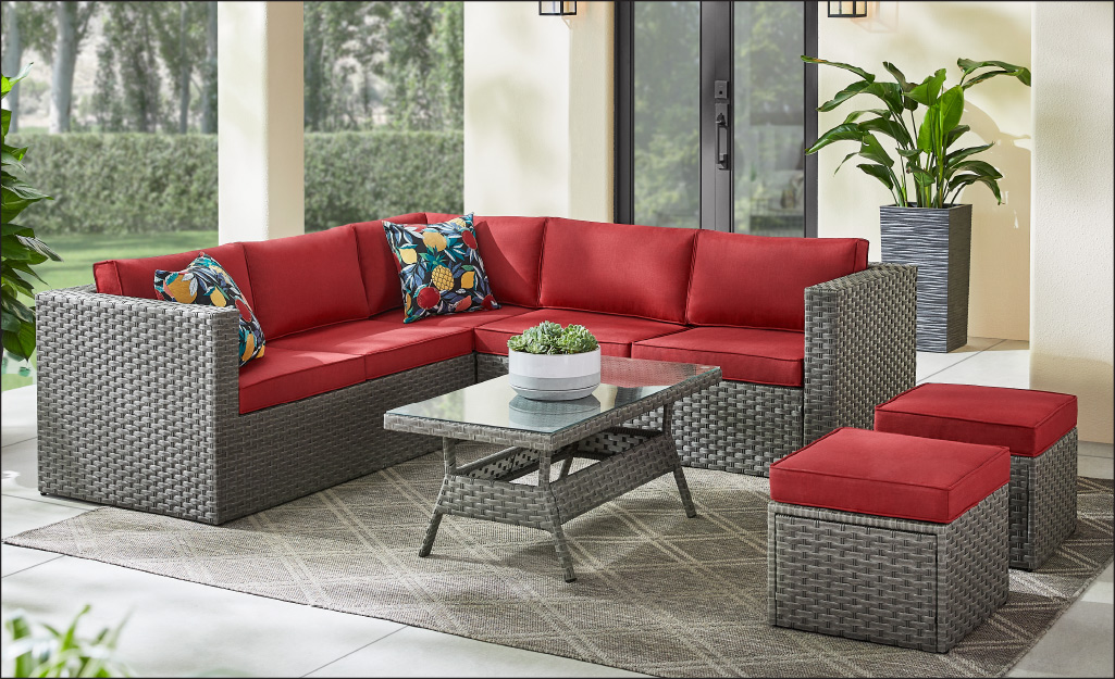 A patio sofa set with red seating cushions.