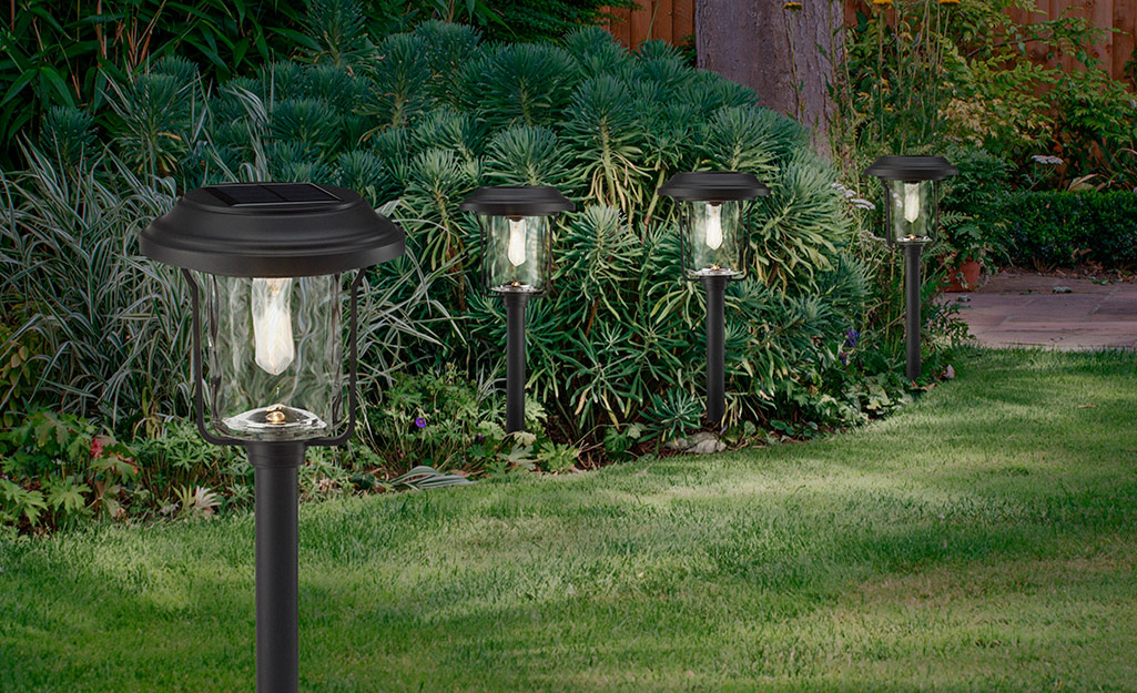 A set of four outdoor lights on a garden path.