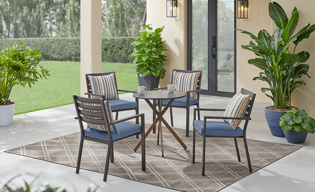 A patio table and chairs next to potted plants.