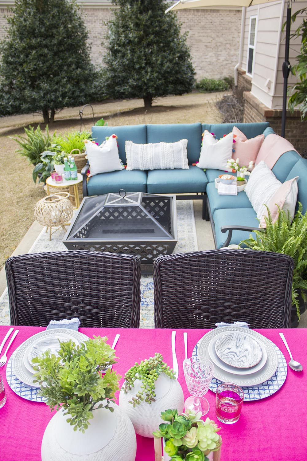 A patio dining table decorated with a bright pink tablecloth and white place settings. A patio dining table decorated with a bright pink tablecloth and white place settings.