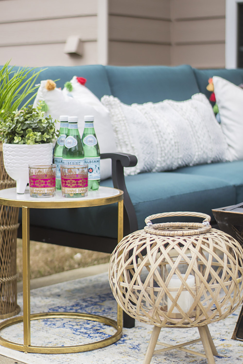 An patio decorated with an outdoor rug, side table, and lantern. An patio decorated with an outdoor rug, side table, and lantern.