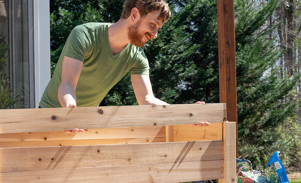A person building a raised garden bed for a square foot garden.