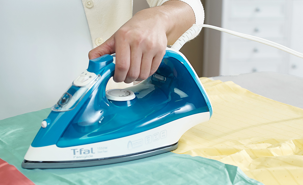 A woman ironing a shirt on an ironing board.