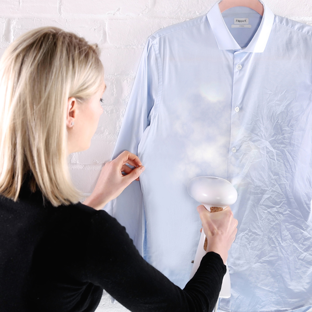 Woman is steaming a blue shirt.
