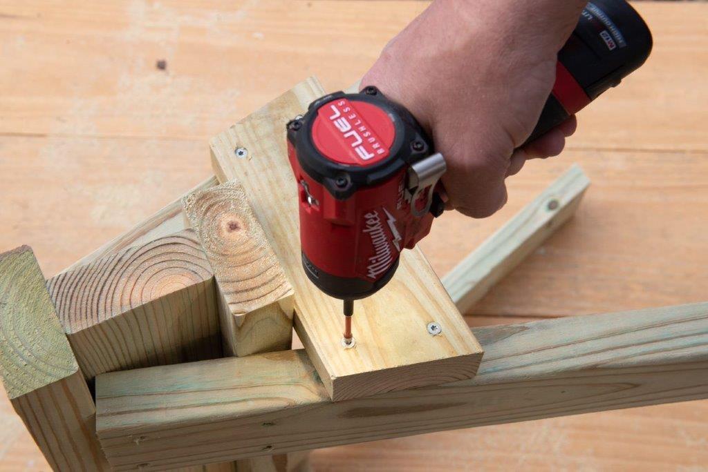 A pro screws in gussets to either side of the sawhorse. A pro screws in gussets to either side of the sawhorse.