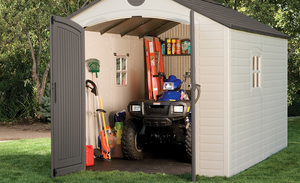 A backyard storage shed showing a string trimmer and other lawn tools.