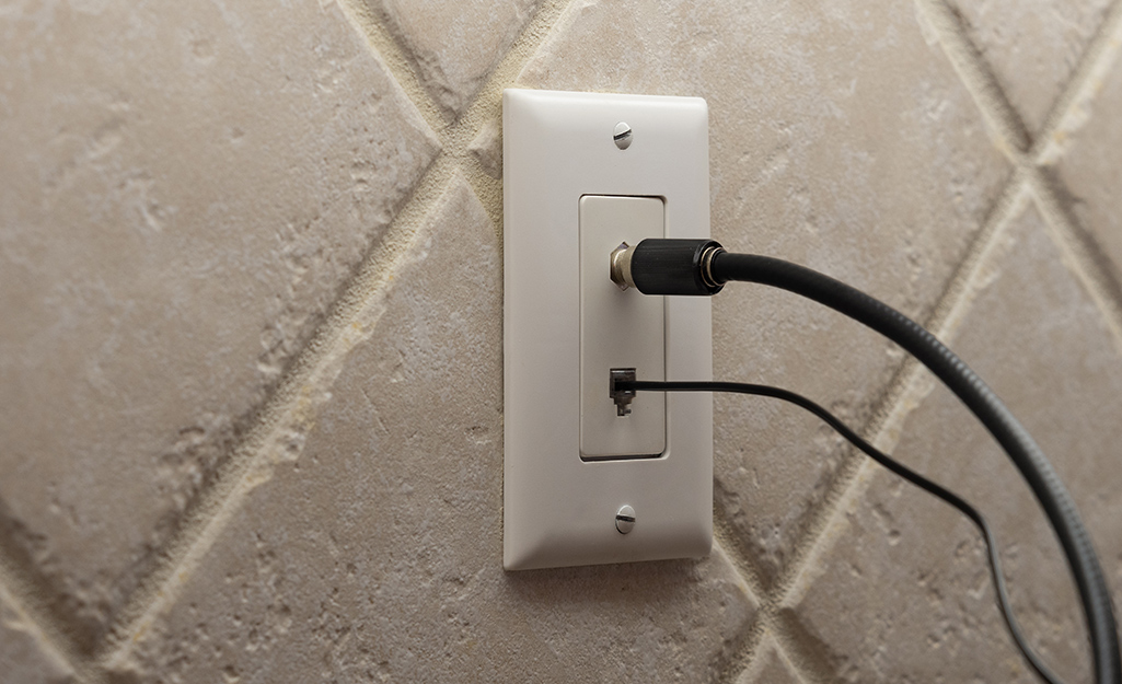 Two types of cables plug into a wall jack.