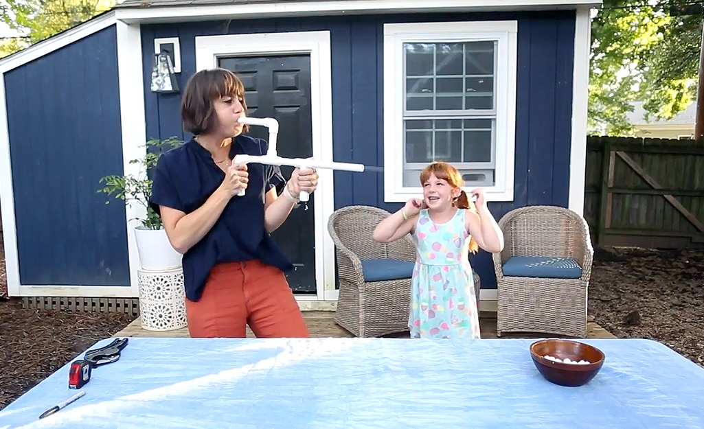 A woman uses a marshmallow cannon. 