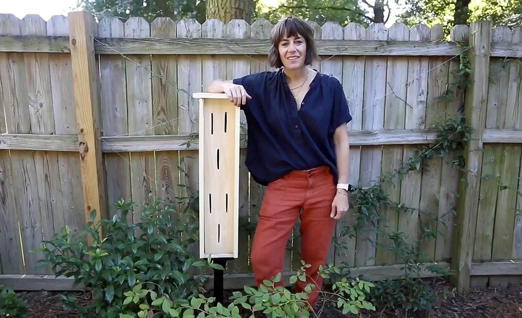 A woman standing beside a completed butterfly house. 