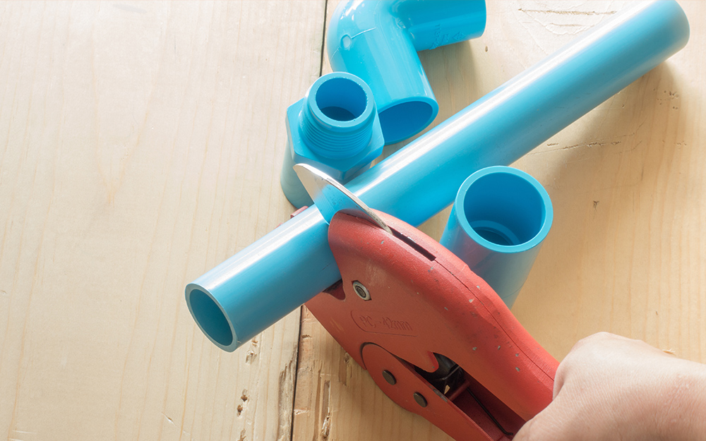 A person uses a tube cutter to cut PVC pipe. A person uses a tube cutter to cut PVC pipe.
