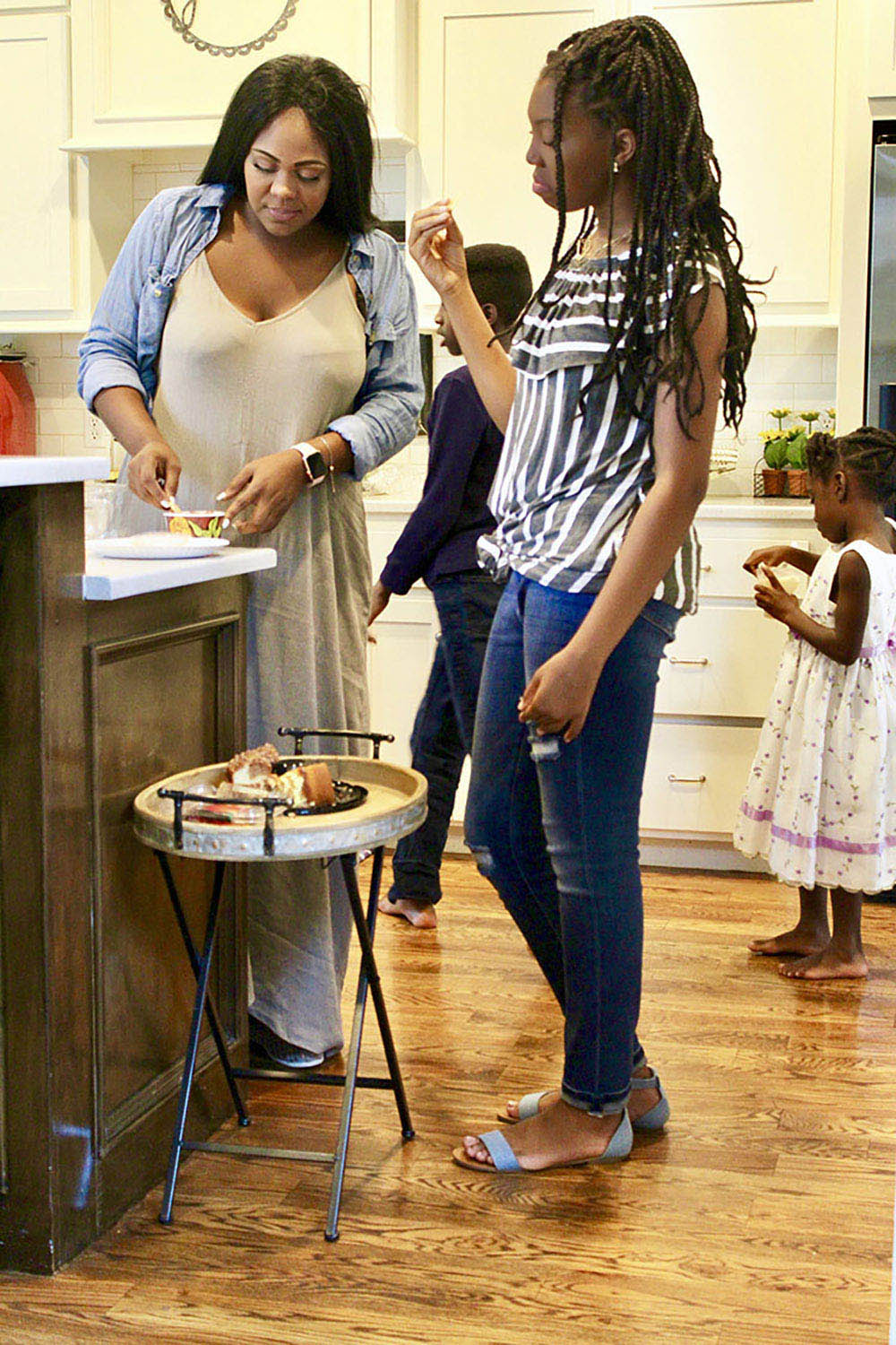 Two women standing in a kitchen with a small child behind them.