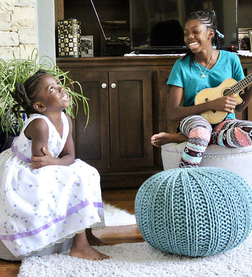 Two children smile while sitting on ottomans and poufs. Two children smile while sitting on ottomans and poufs.