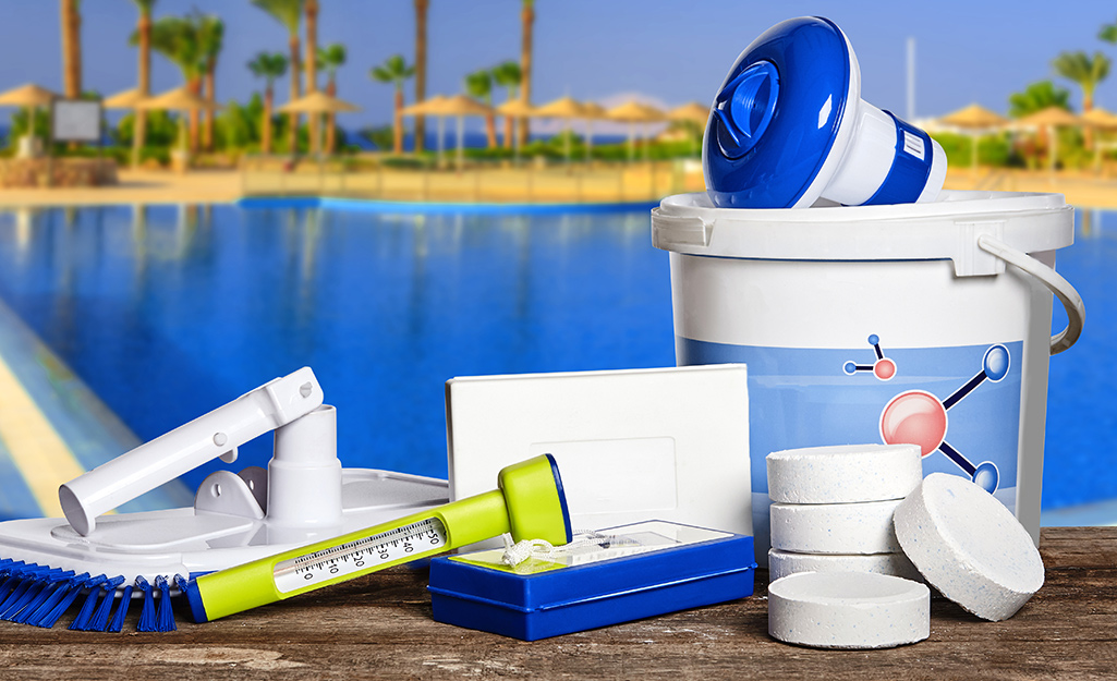 Chlorine tablets, testers and other pool cleaning supplies spread on a deck.