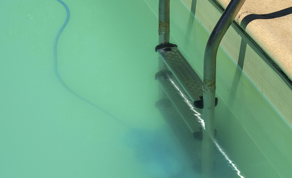 A ladder goes down into a cloudy pool.