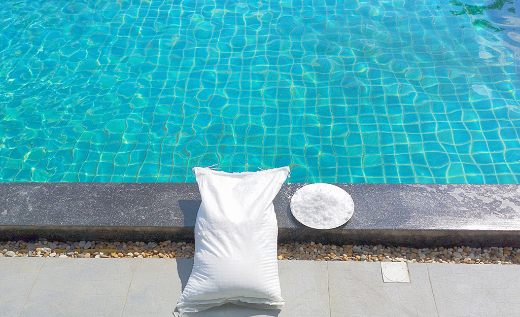 A bag of pool chemicals lays next to a sparkling pool