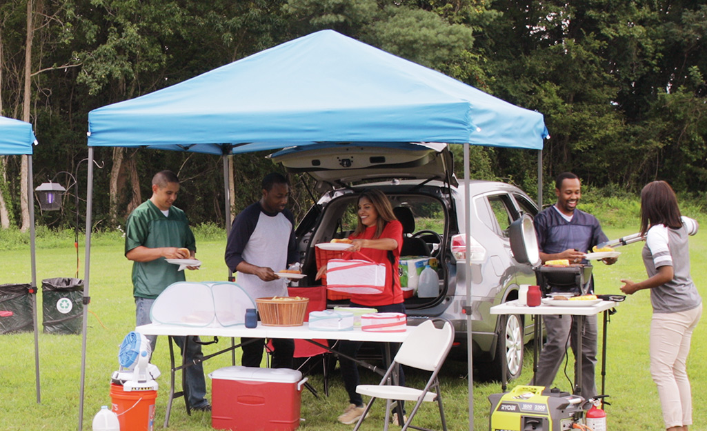 Friends tailgate under a pop-up tent near their truck.