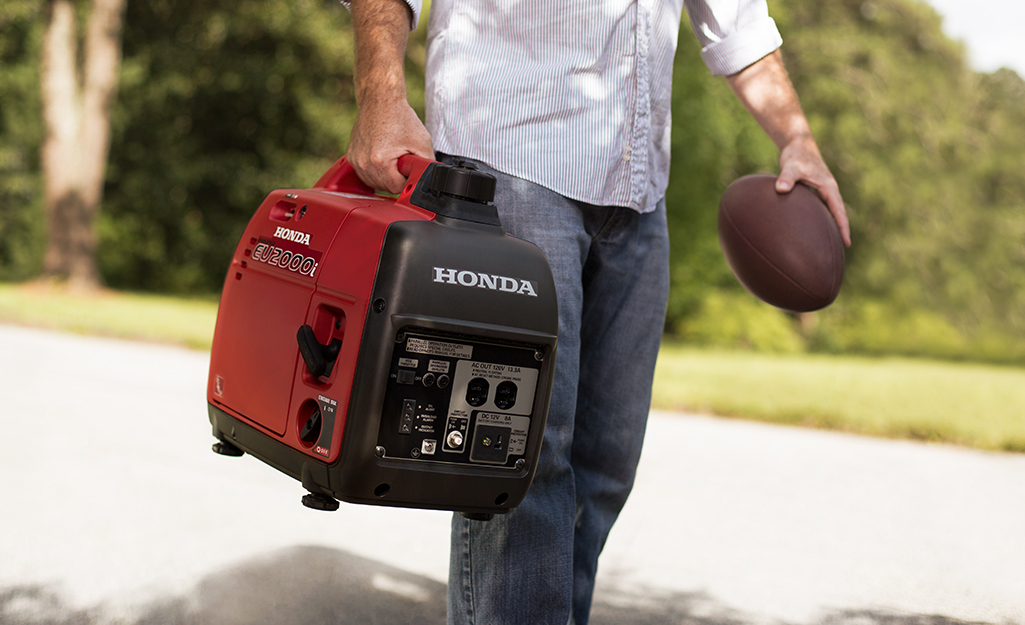 A man carries a generator in one hand and a football in the other. 