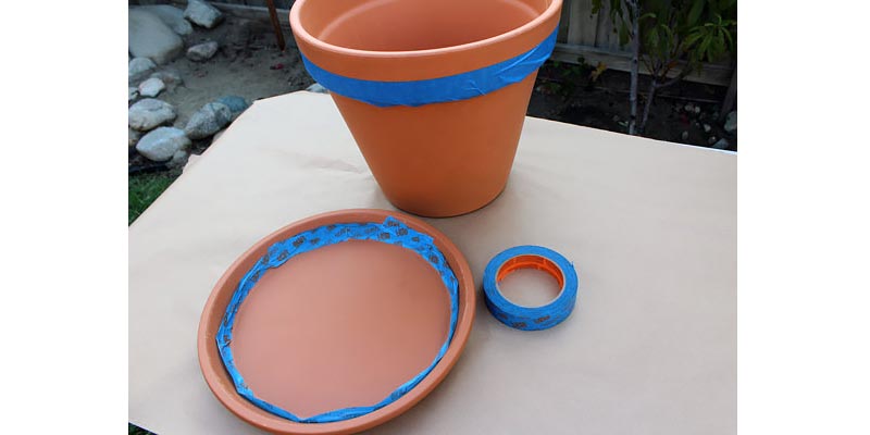 A terra cotta pot and saucer with painter's tape.