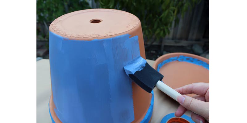 A person painting a terra cotta pot.