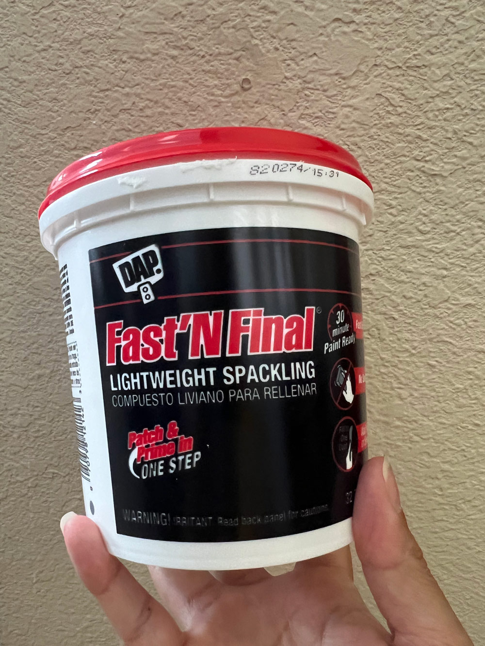 A person holding a Fast’N Final spackle. A person holding a Fast’N Final spackle.