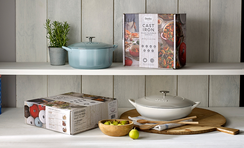 Two Dutch ovens next to their boxes on a counter.