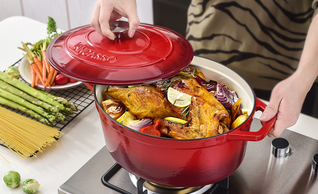 A person lifting a lid on a Dutch oven to check on the chicken inside.