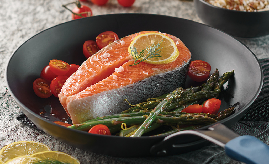 Salmon, asparagus and cherry tomatoes in a carbon steel pan.