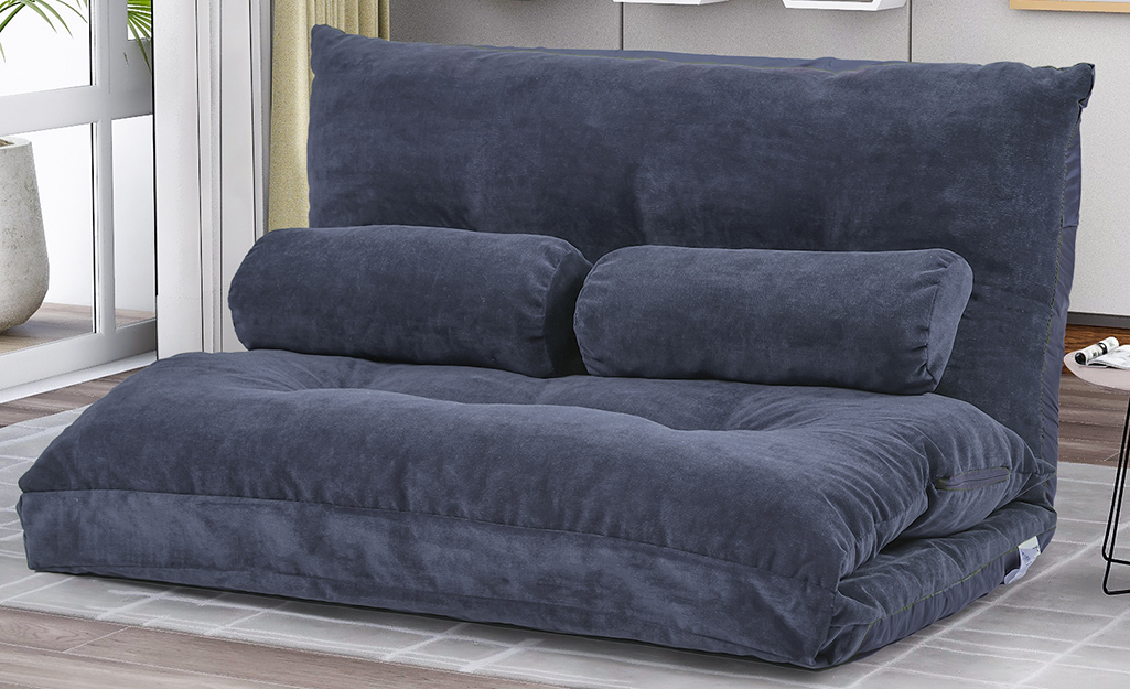 A blue trifold futon in a room.