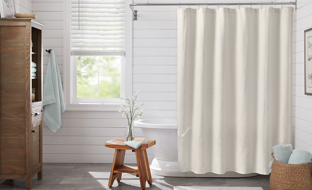 A neutral shower curtain surrounding a tub.