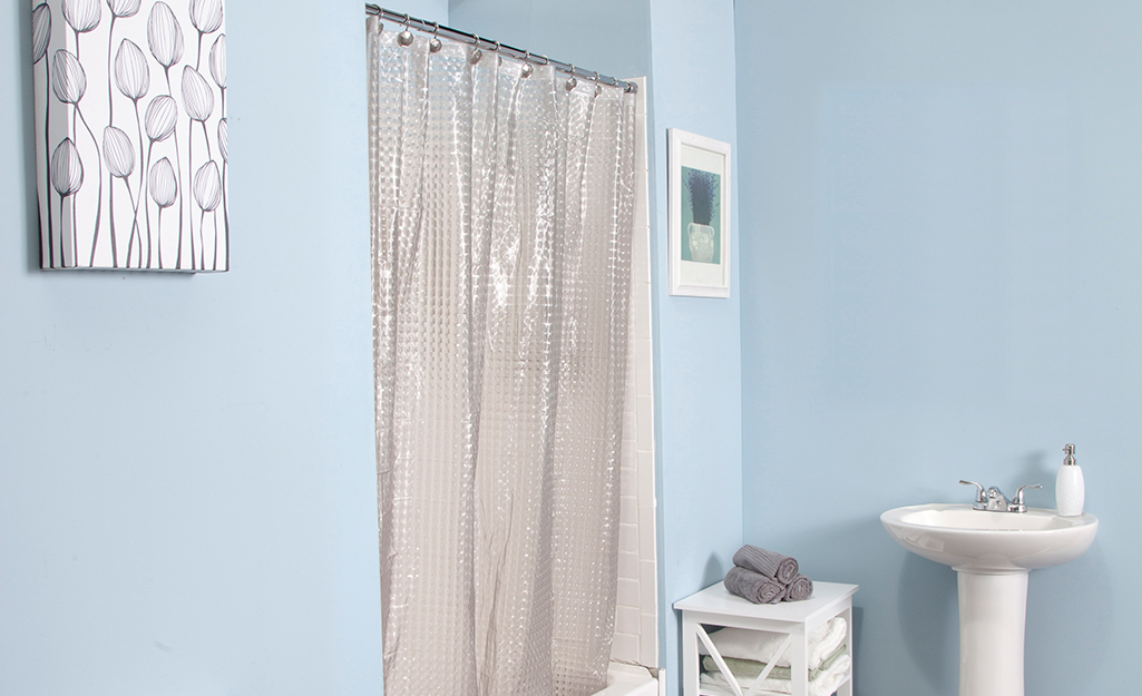 A clear shower curtain liner inside a shower stall.