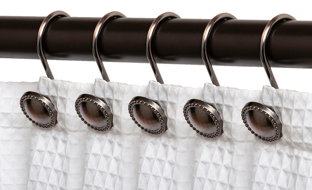 A shower curtain rod hung with matching shower curtain hooks.