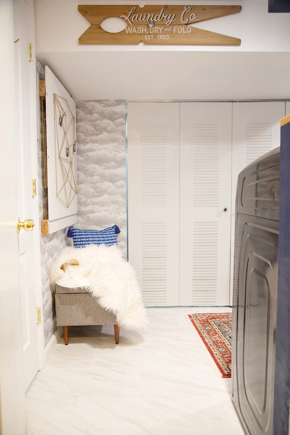 A large laundry room with white floor and a wall with cloud wallpaper.