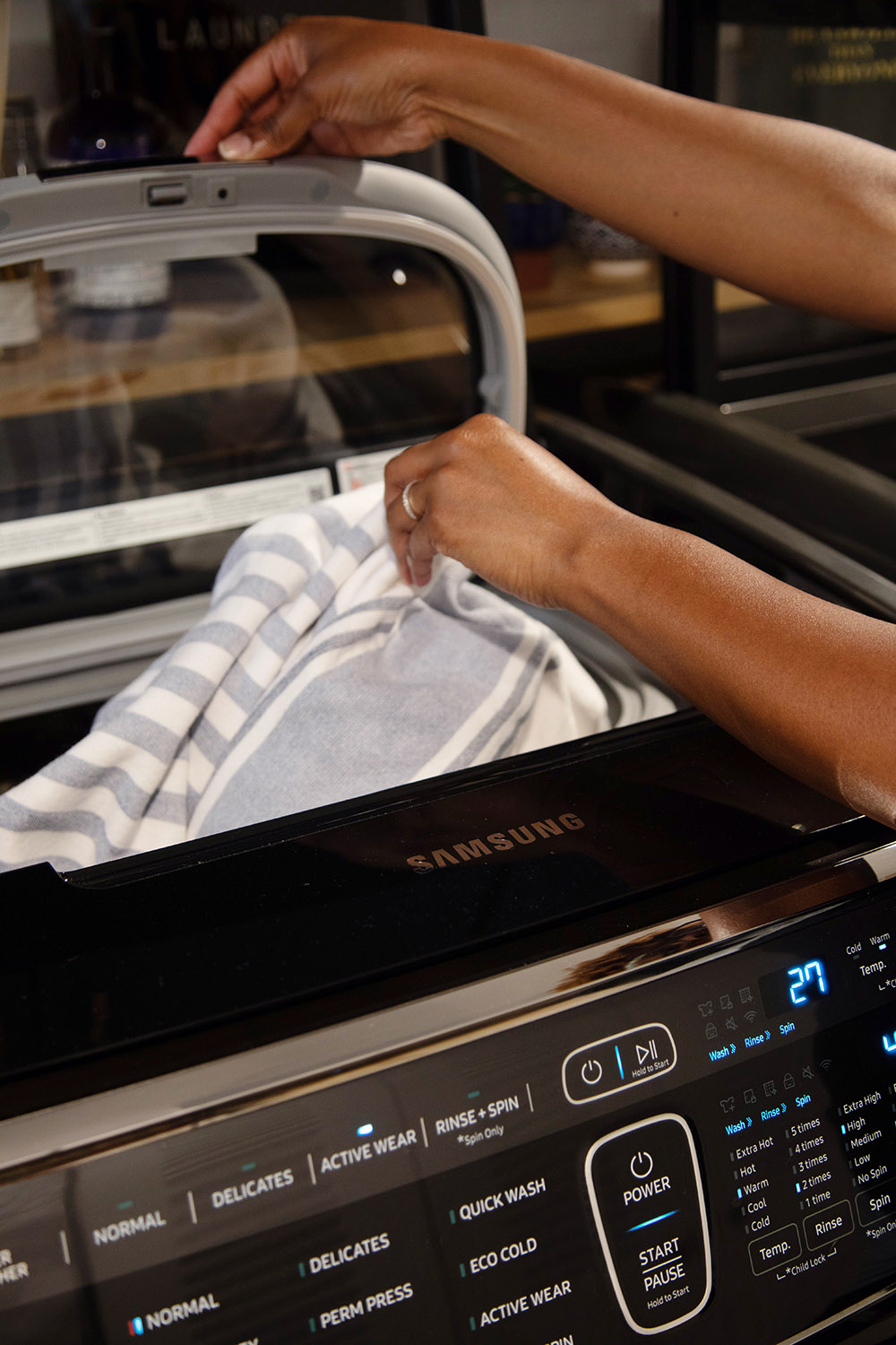 A person putting clothing in the top of a Samsung FlexWash.