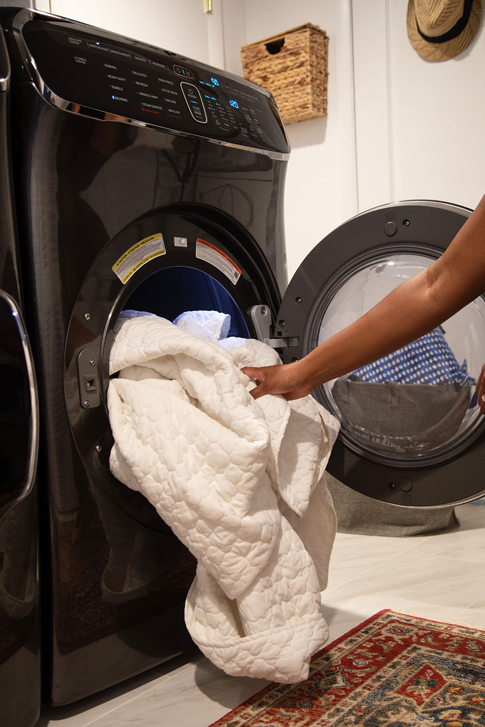 A person removing bedding from a Samsung FlexDry.